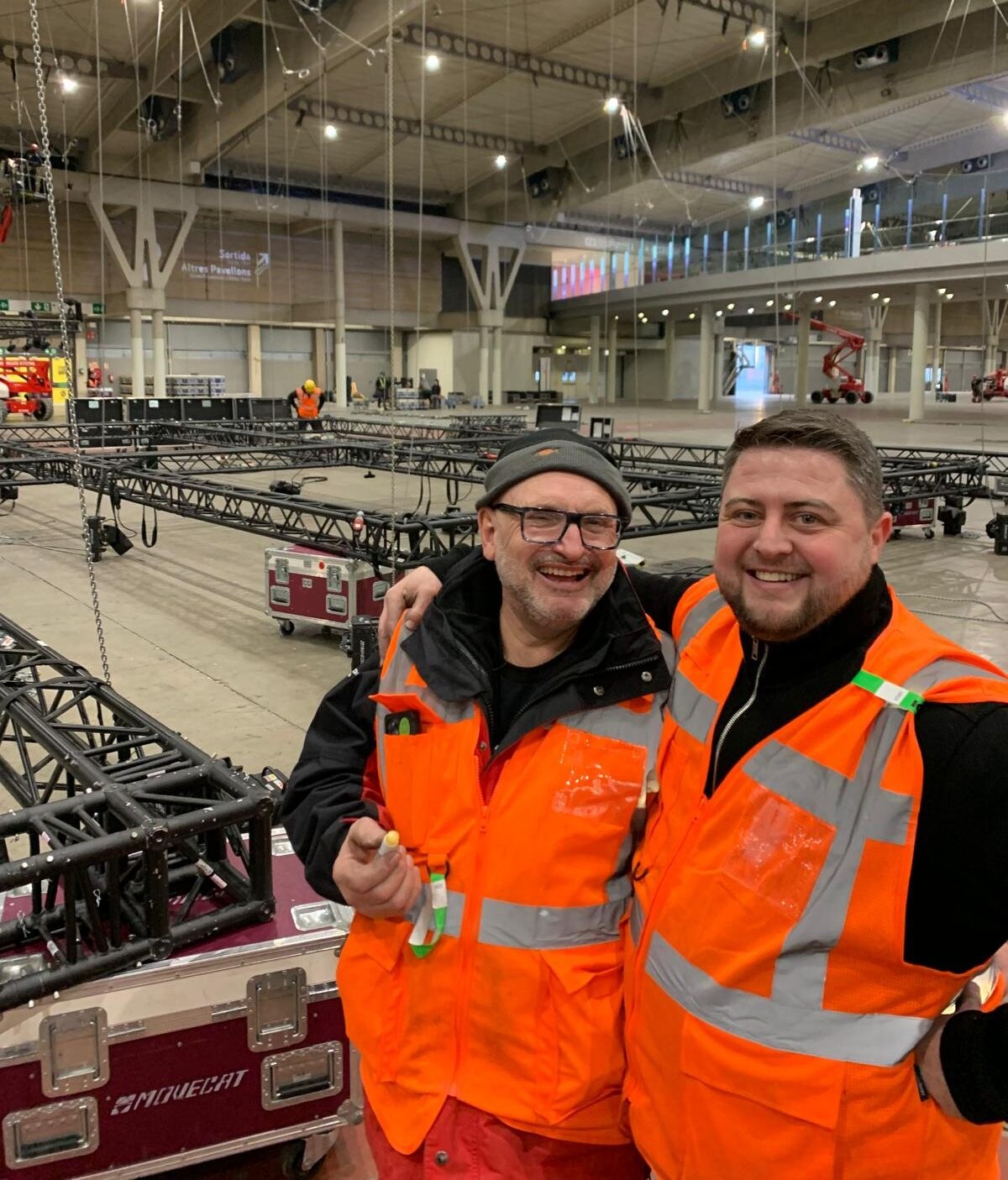 Exporigging crew in high visibility clothing beside black truss during an exhibition build